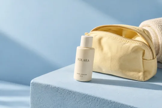 Solara Travel Cleanser beside a yellow travel bag on a sunlit blue ledge